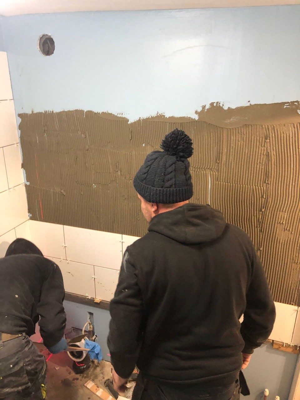 Tilers preparing a bathroom wall