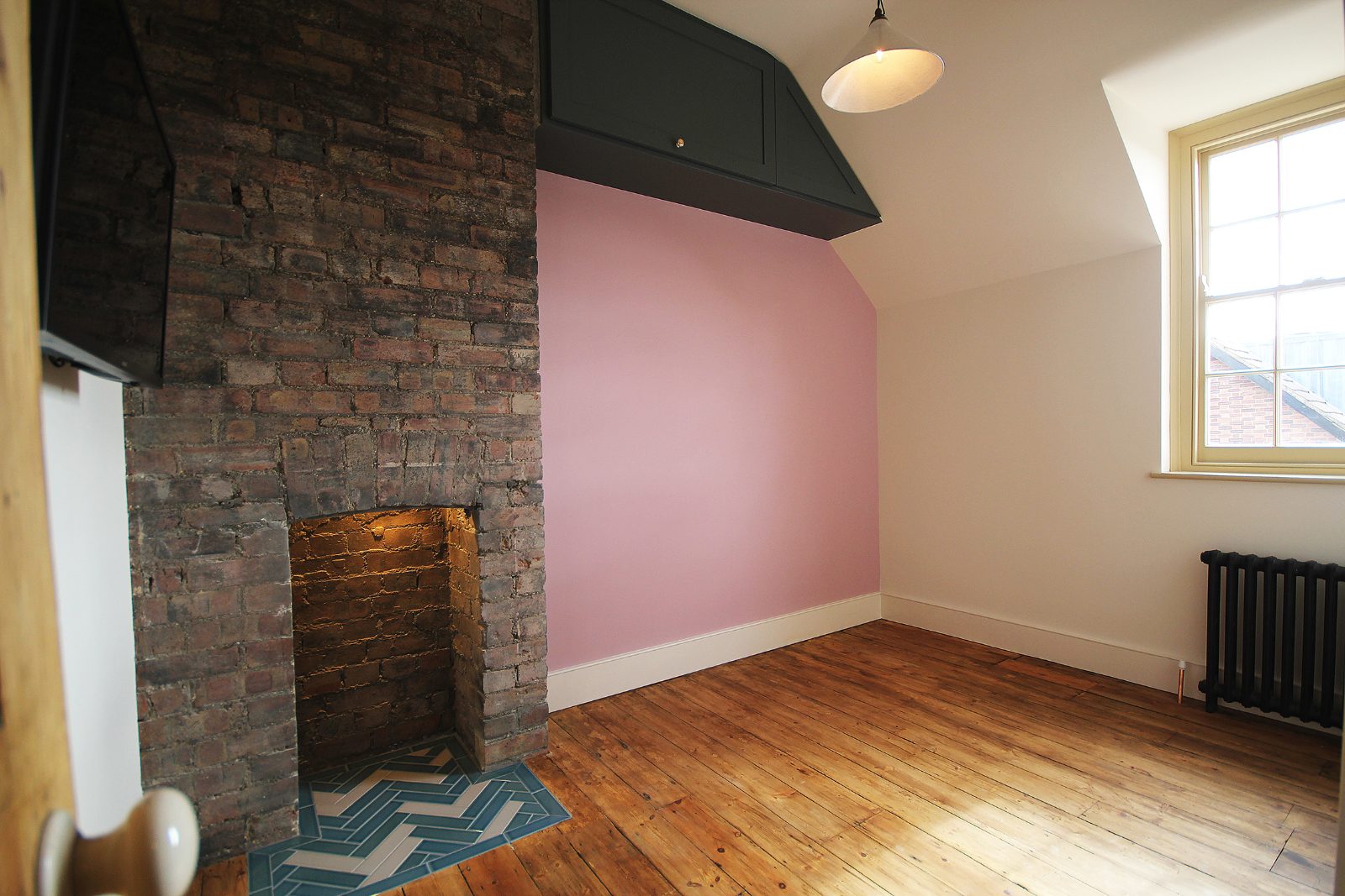 Restored room with an exposed brick chimney breast and timber floor