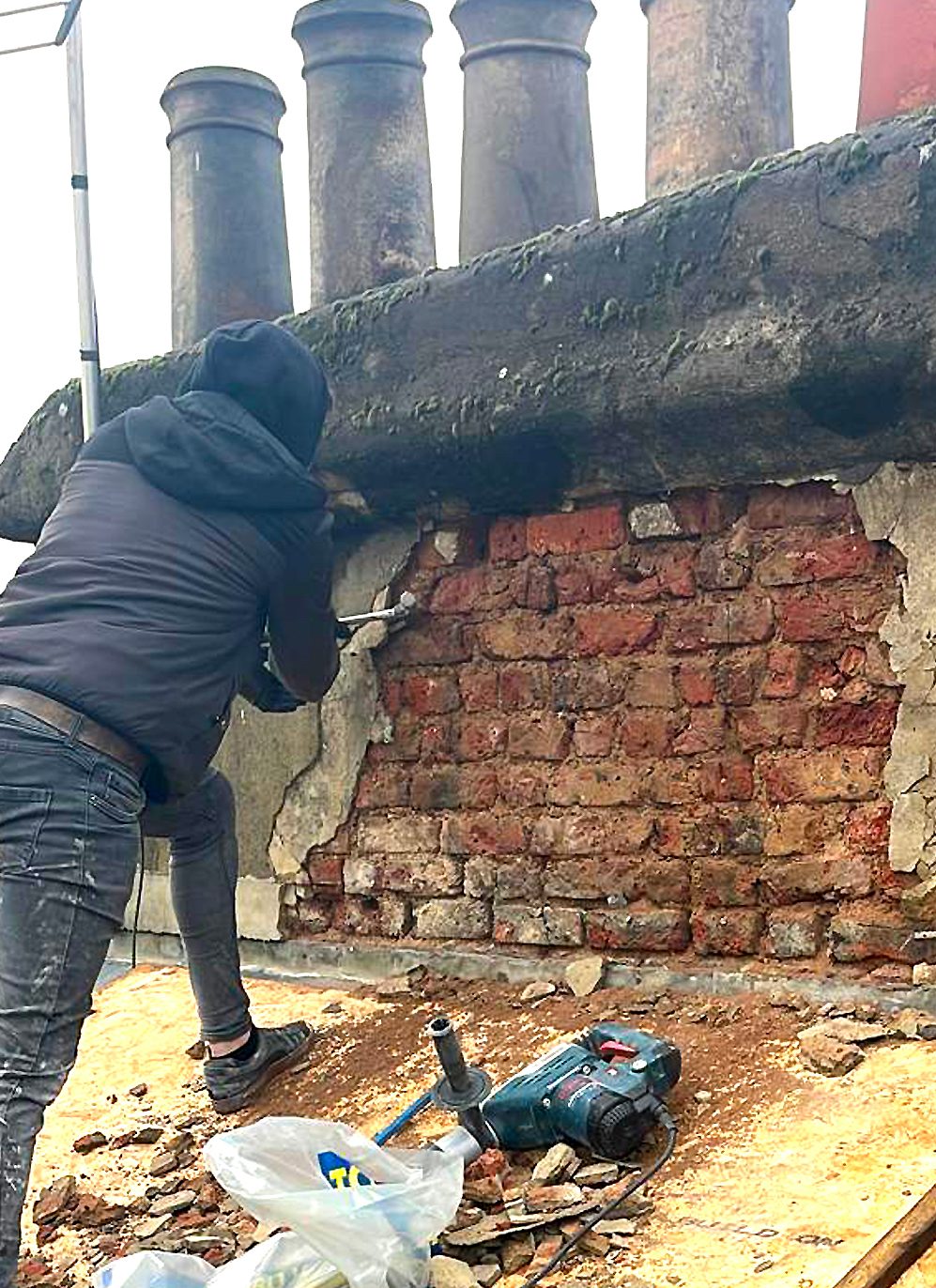 Cutting back failed render to repair the brickwork below a chimney