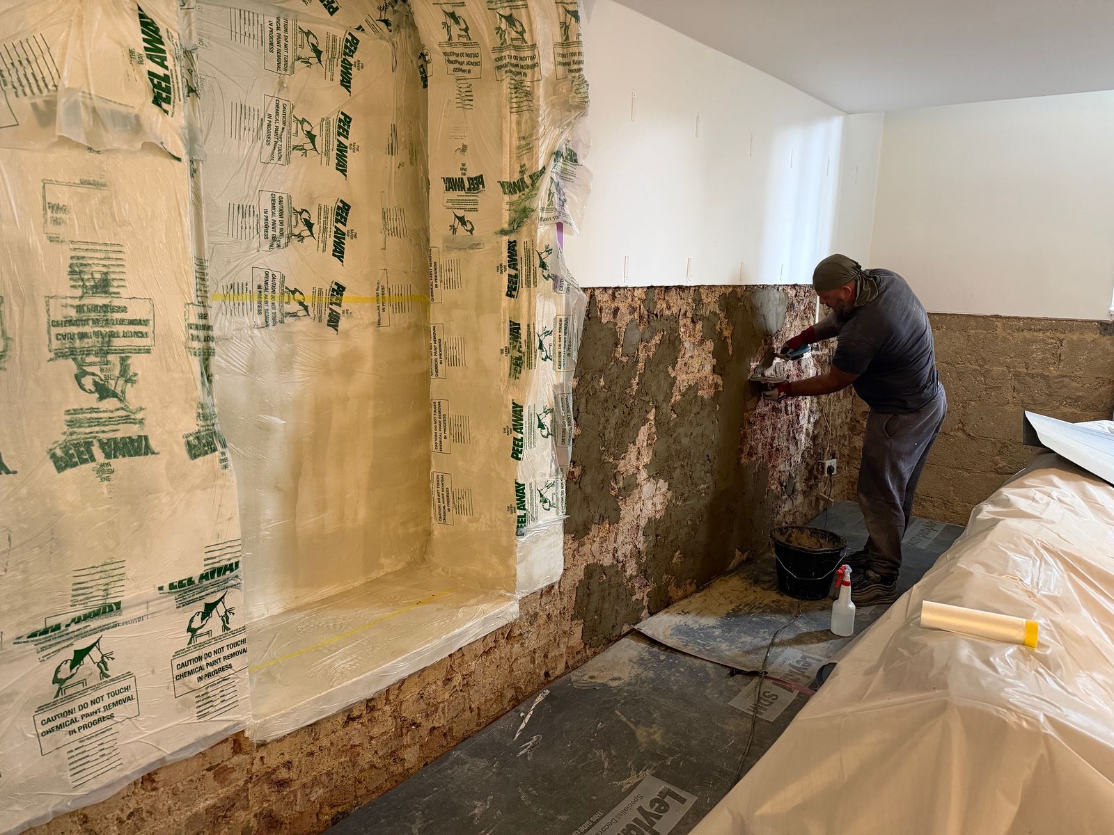 Damp render removed from the lower walls, with paint stripper on the stone arches