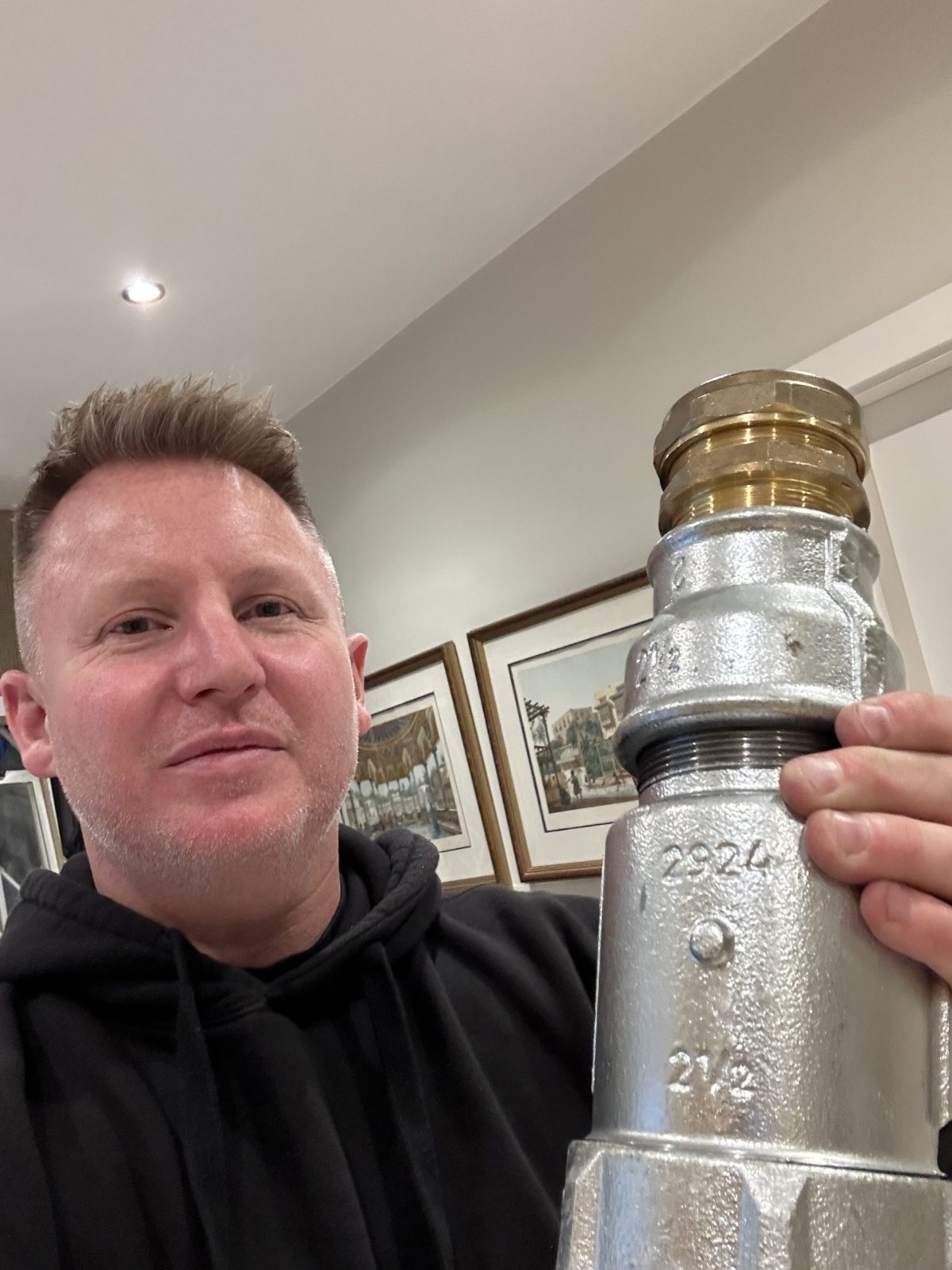 Ross holding a large replacement plumbing fitting