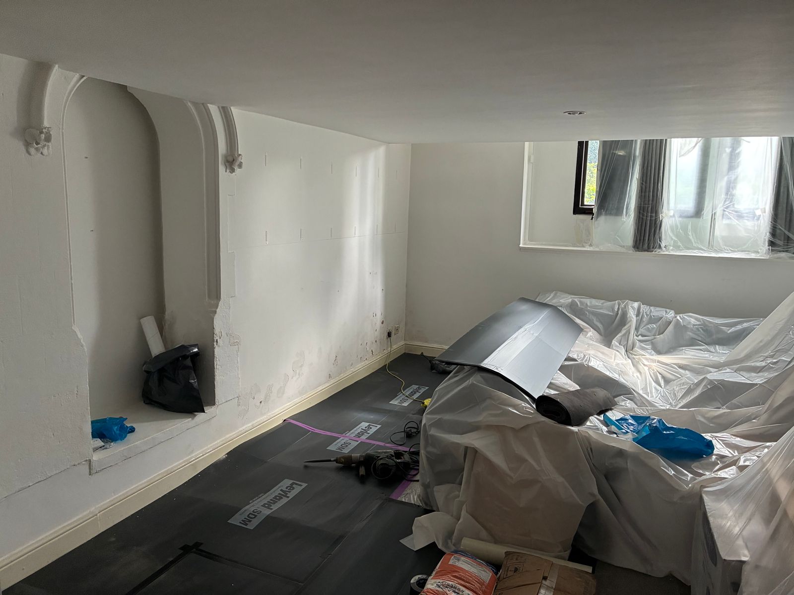 Room with damp-affected wall stripped back before treatment