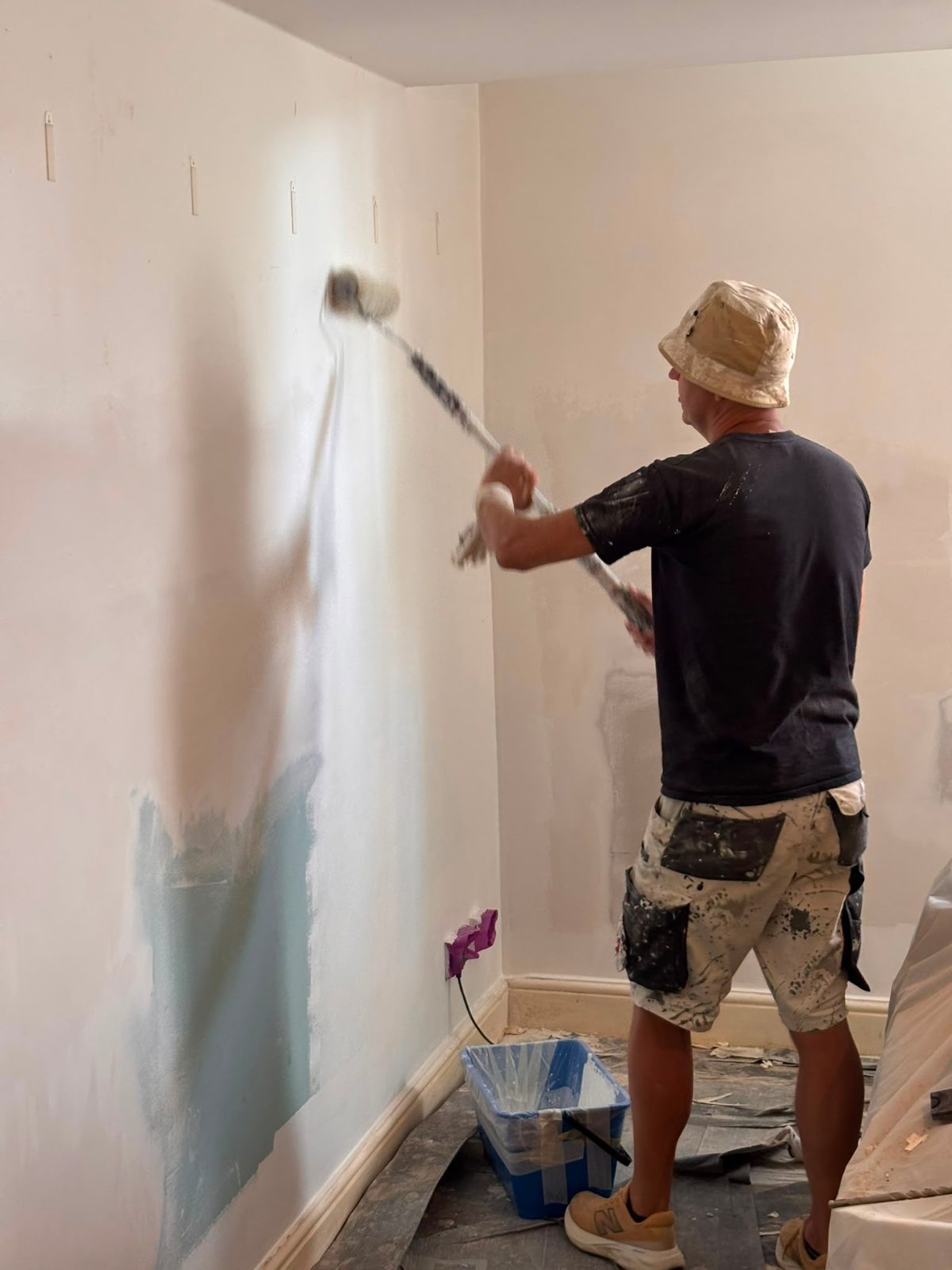 Decorator painting a repaired wall with a roller