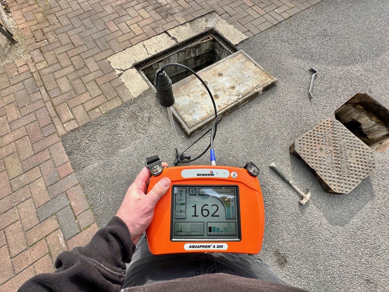 Acoustic leak detector in use beside an open inspection chamber